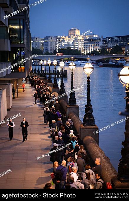 15 September 2022, Great Britain, London: Numerous people stand in a long queue on the Thames between Millennium Bridge and Parliament to say goodbye to the...