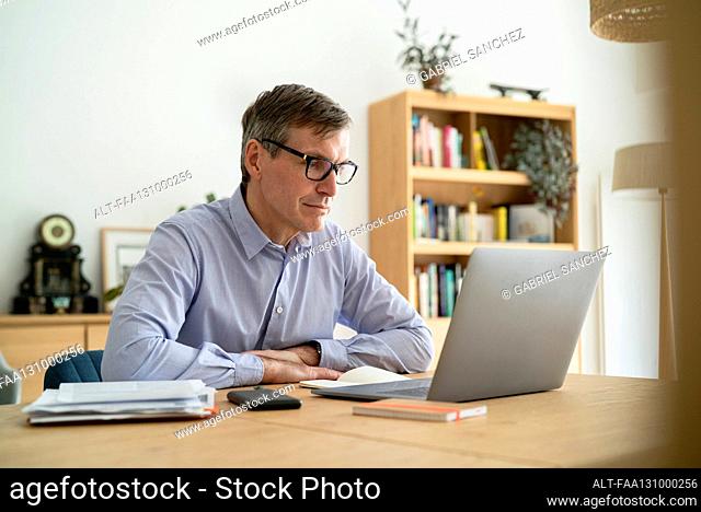 Senior businessman sitting at desk while using laptop
