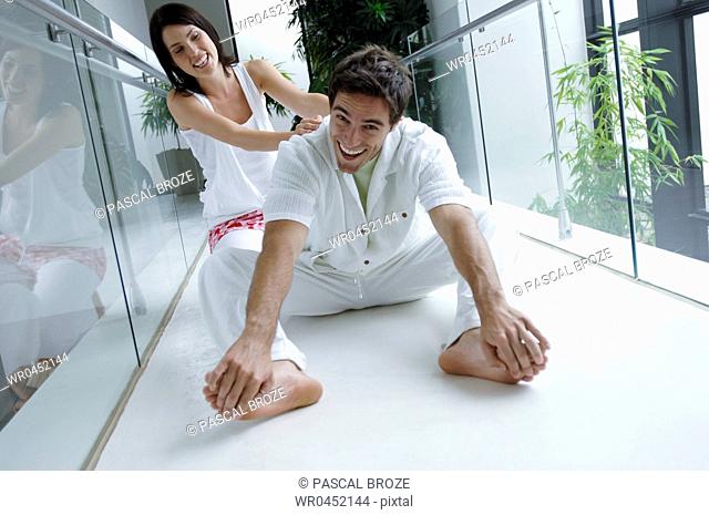 Mid adult woman helping her husband practice yoga and smiling