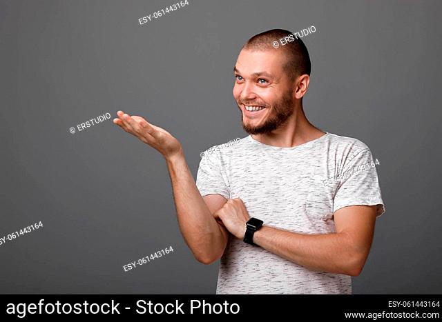 Portrait of a young smiling man pointing copy space