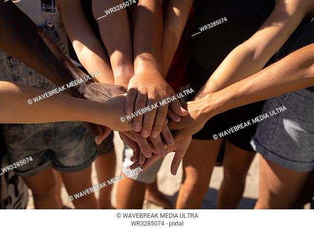 Mid section of group of multi ethnic volunteers forming hand stack on the beach