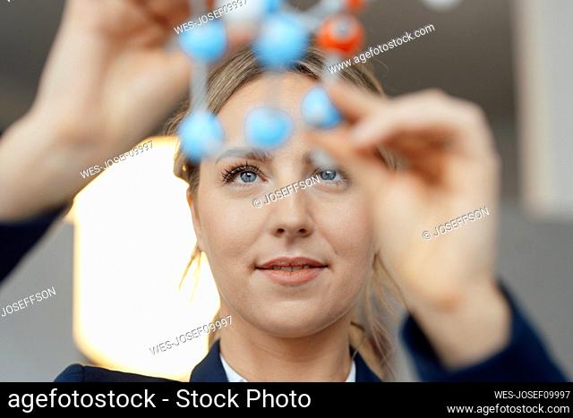 Businesswoman examining molecular model in office