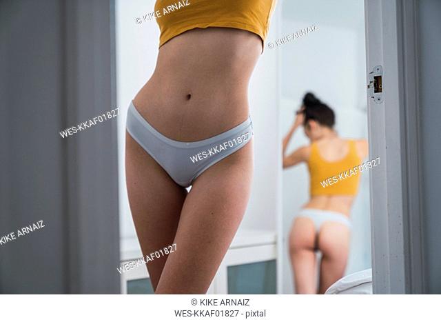 Young woman in underwear at home reflected in mirror