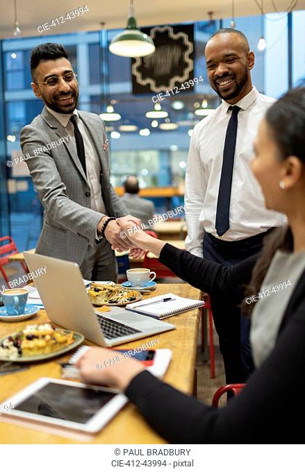 Business people handshaking, working in cafe