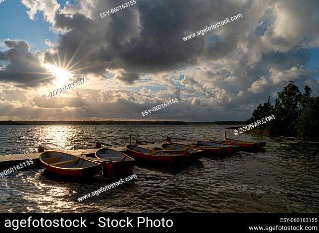 Several colorful rowbaots tied to a wooden floating dock in a beautiful lake landscape