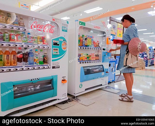 woman buys drinks in the automatic machine of Yonago, Japan, 08.08.2017