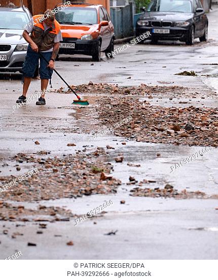 A resident cleans a street from mud in Elzach, Germany, 06 May 2013. Heavy thunderstorms have caused flooding and severe damages in Elzach