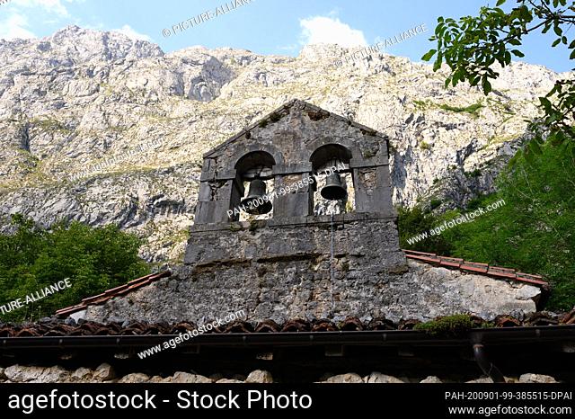 07 August 2020, Spain, Bulnes: The bell gable of the parish church of San Martin, built in quarry stone in front of the limestone cliffs in the Picos de Europa...
