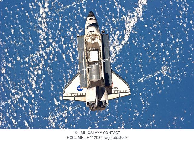Backdropped by a blue and white part of Earth, space shuttle Discovery is featured in this image photographed by an Expedition 26 crew member as the shuttle...