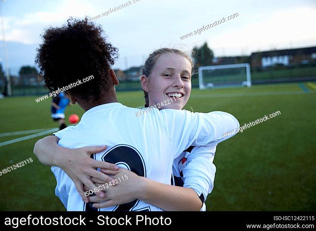 UK, Female soccer team members embracing in field