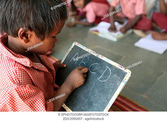 Boy writing on a slate with chalk at ashram school, Rangapura, Zabua district, Madhya Pradesh