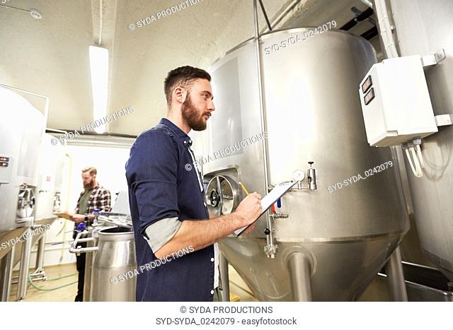 men with clipboard at craft brewery or beer plant