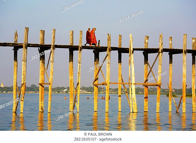 Monks crossing the U Bein Bridge across the Taungthaman Lake in Amarapura, Mandalay, Myanmar (Burma) believe to be the oldest and longest teakwood bridge in the...