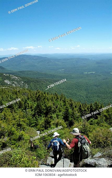 Hikers descend Baldface Circle Trail the summit of North Baldface Mountain in the White Mountains, New Hampshire USA during the spring months