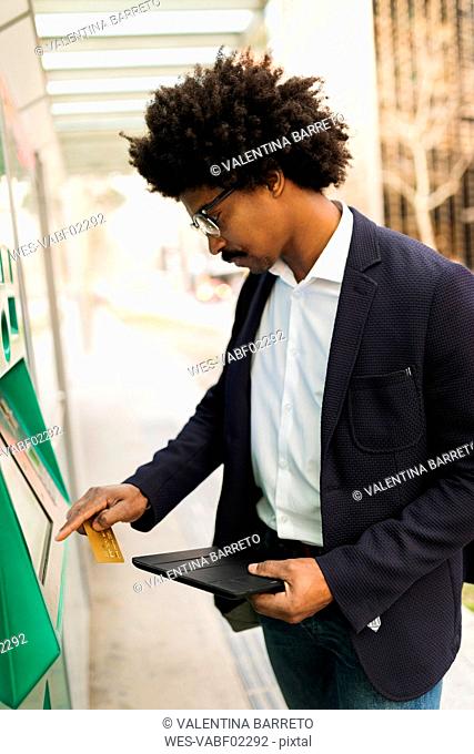 Spain, Barcelona, businessman using ticket machine at tram stop in the city