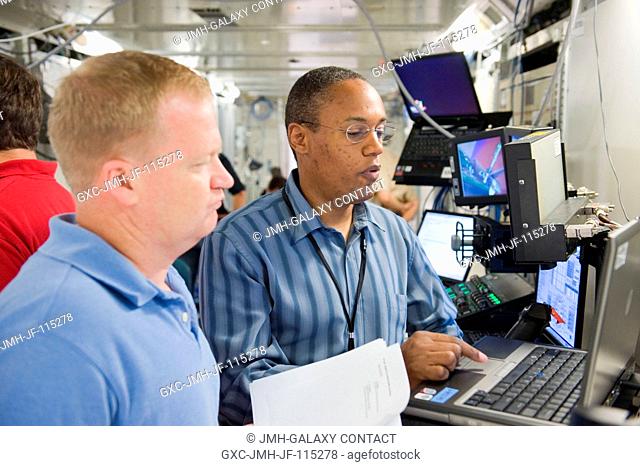 NASA astronauts Eric Boe (foreground), STS-133 pilot; and Alvin Drew, mission specialist, participate in a robotics training session in the Jake Garn Simulation...