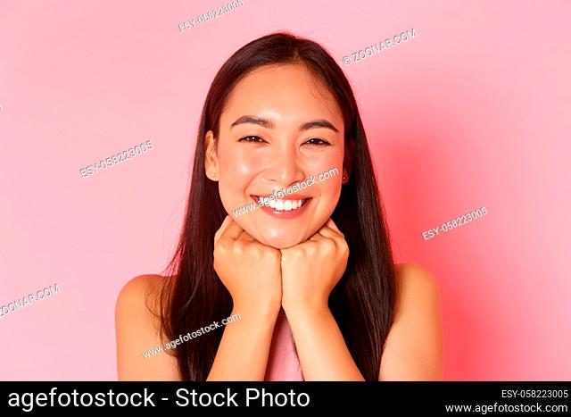 Beauty, fashion and lifestyle concept. Close-up of gorgeous happy asian girl, looking dreamy and delighted, leaning head on hands and smiling carefree with...