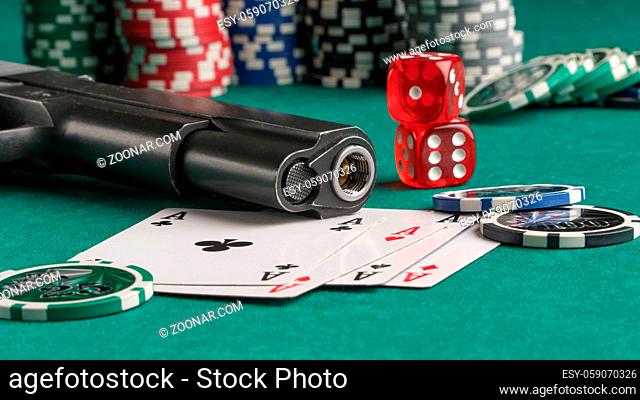 Poker chips, cards and gun on a green background. The concept of gambling and entertainment. Casino and poker