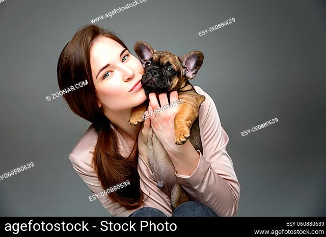 beautiful young woman holding french bulldog puppy dog. happy expression. copy space