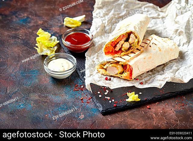 Eastern traditional shawarma with chicken and vegetables, Doner Kebab with sauces on slate. Fast food. Eastern food
