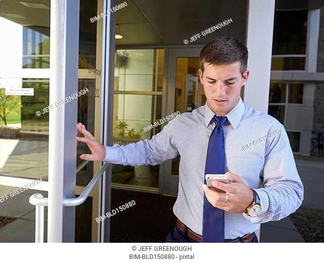 Caucasian businessman using cell phone outside office building