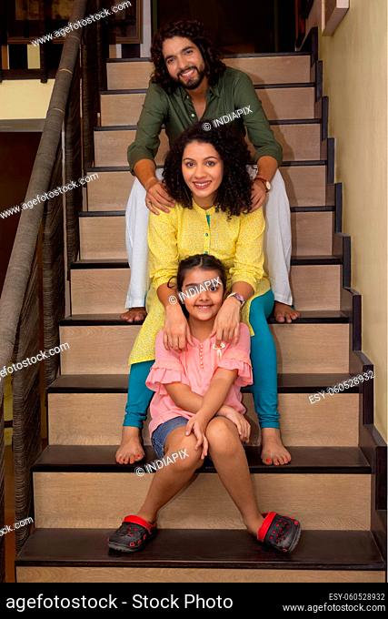 Family members posing in front of camera while sitting on stairs at home