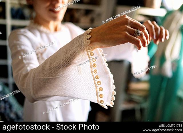 Woman wearing new white dress with long sleeve in wardrobe at home
