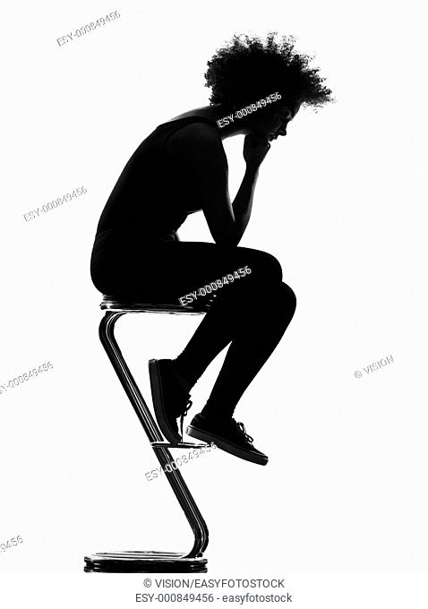 beautiful funny young afro american woman sitting on footstool pensive in silhouette shadow on studio isolated white background
