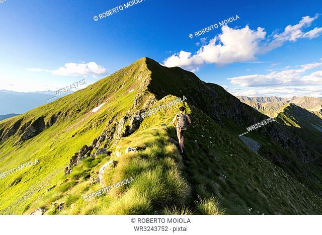 Hiker on steep ridge on the ascent towards Monte Azzarini, San Marco Pass, Albaredo Valley, Orobie Alps, Lombardy, Italy, Europe