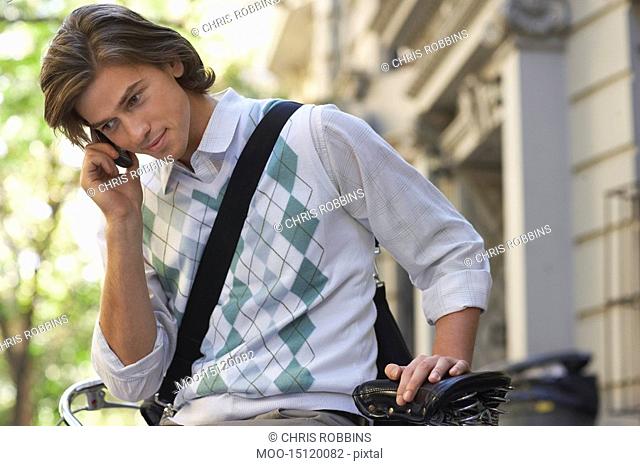 Man sitting on bicycle talking on mobile phone