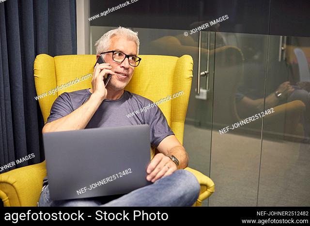 Businessman talking on phone and using laptop