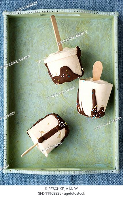 Homemade vanilla ice cream sticks with chocolate glaze on a tray