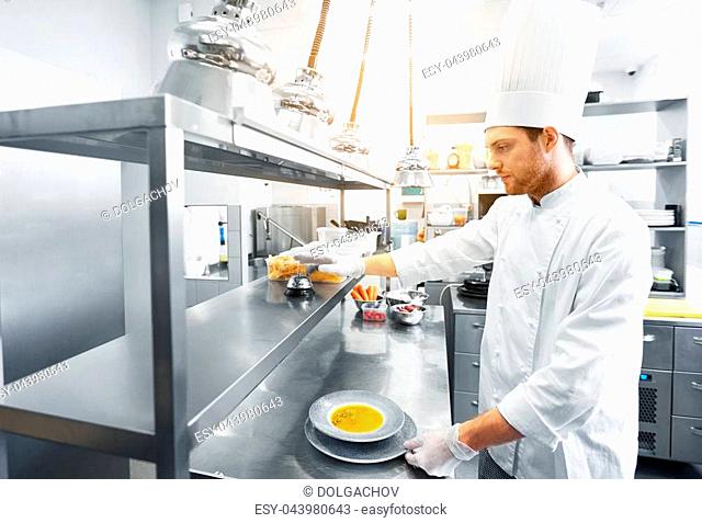 food cooking, profession and people concept - happy male chef cook with plate of soup and salad at restaurant kitchen table