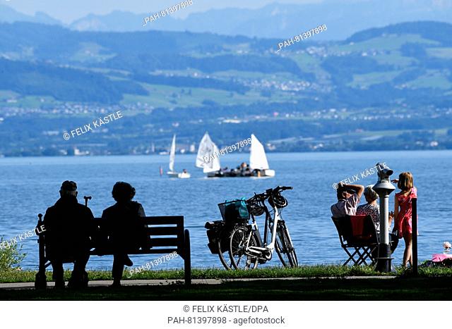 A couple sits on a bench on the banks of flooded Lake Constance in Fischbach, Germany, 20 June 2016. To the side another couple can be seen sitting on camping...