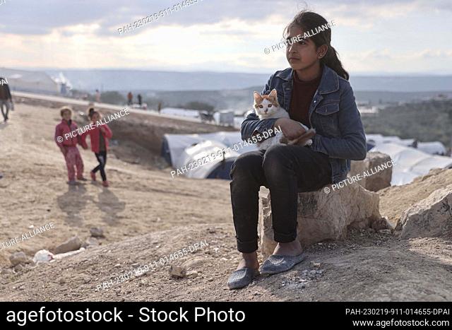 19 February 2023, Syria, Salqin: A girl holds her cat as she sits near an emergency shelter built for those affected by the earthquake that ravaged the...