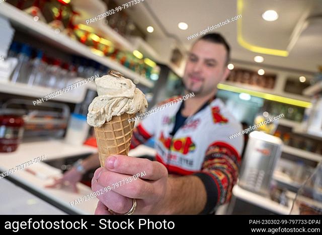 PRODUCTION - 01 March 2023, Baden-Württemberg, Rottenburg am Neckar: Thomas Micolino, owner of Eiscafé Rino, shows off an ice cream made partly of cricket flour...