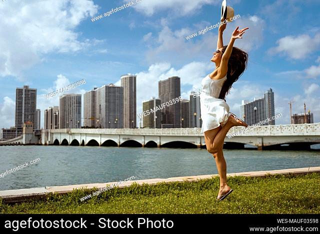 Excited female tourist jumping over grass by bay
