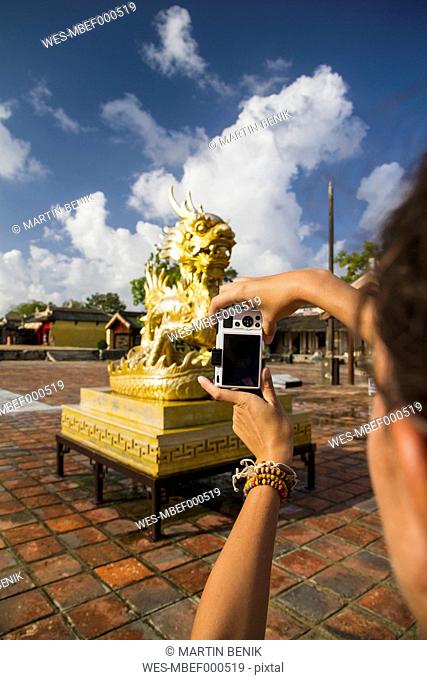 Vietnam, Hue, Young woman taking photograph of Can Chanh palace