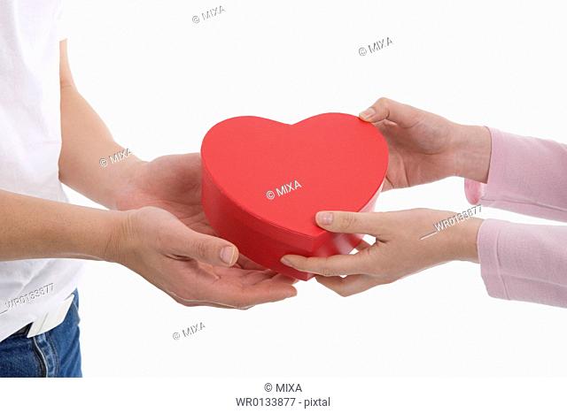 Woman giving man heart-shaped box