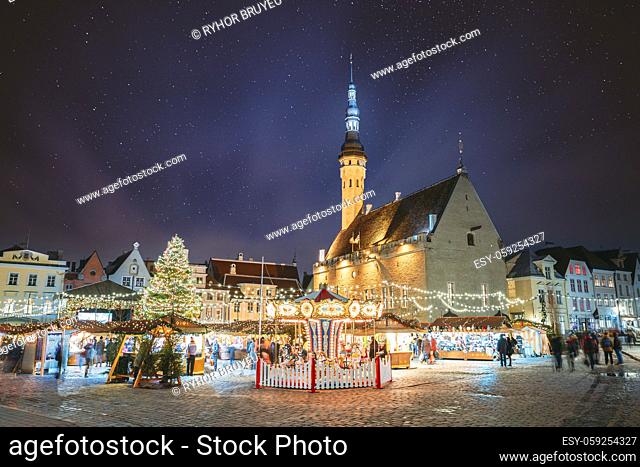 Tallinn, Estonia. Night Stars Sky Above Traditional Christmas Market And Carousel On Town Hall Square. Christmas Tree. Famous Landmark