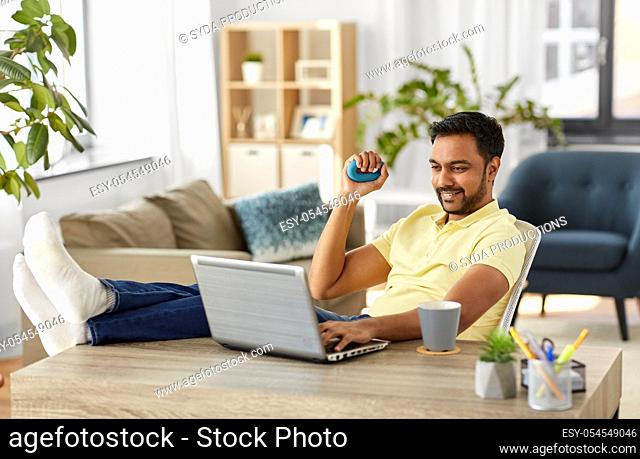 man with laptop and hand expander at home office