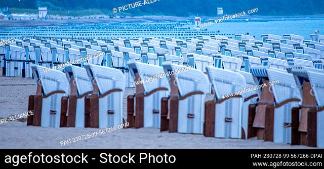 28 July 2023, Mecklenburg-Western Pomerania, Rostock: Empty beach chairs stand on the Baltic Sea coast in Warnemünde in the morning