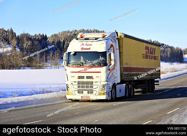 Beautifully customised white Volvo FH truck M. Leino pulls DHL freight trailer on highway 52 on sunny day of winter. Salo, Finland. February 12, 2021