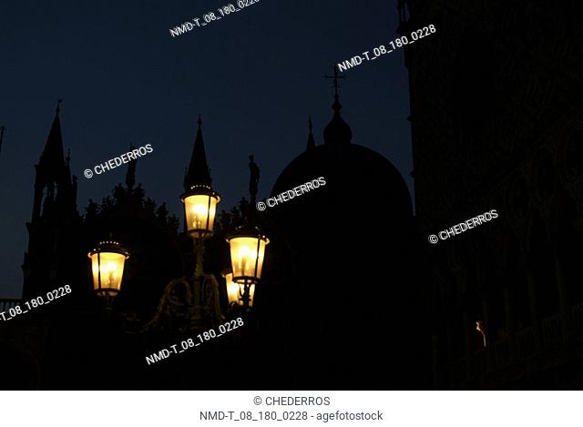 Low angle view of lamps lit up in front of a cathedral at night, St. Mark's Cathedral, Venice, Veneto, Italy