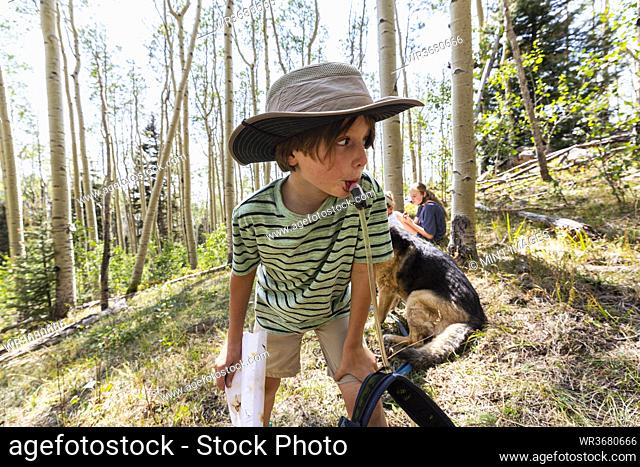 7 year old boy drinking water from hydration pack in forest of Aspen trees