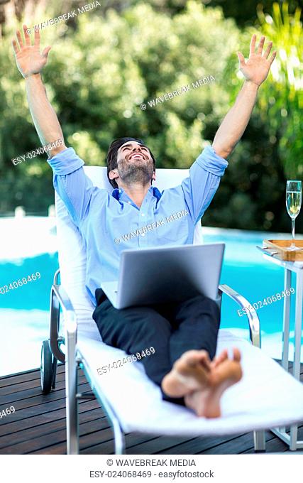 Excited man using a laptop near pool