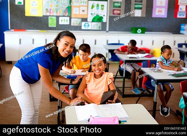 Portrait of african american female teacher and disabled girl smiling in class at elementary school