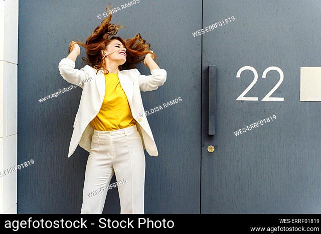 Businesswoman in white pant suit, standing in front of entrance door