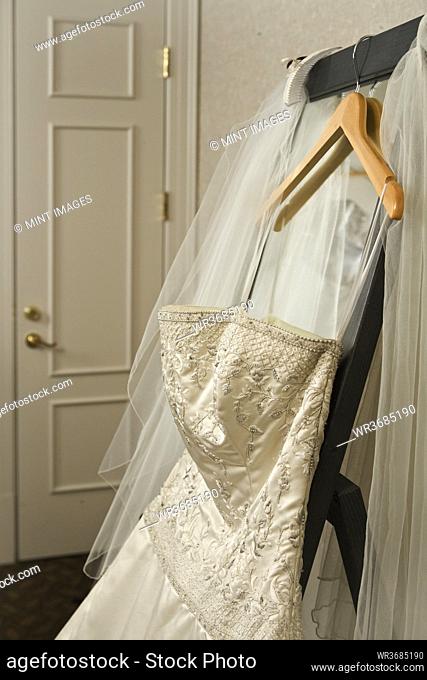 Wedding dress and veil hanging on rack in hotel room