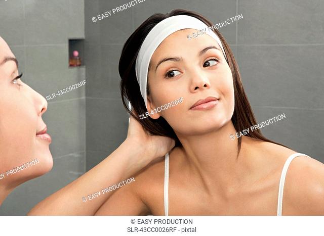 Woman examining her hair in mirror